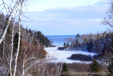 The river is frozen over while Lake Superior remains open in the distance